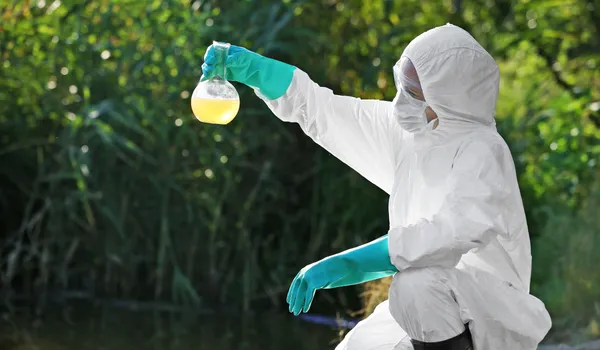 2. image of reasearcher holding up an example of contaminated soil and water